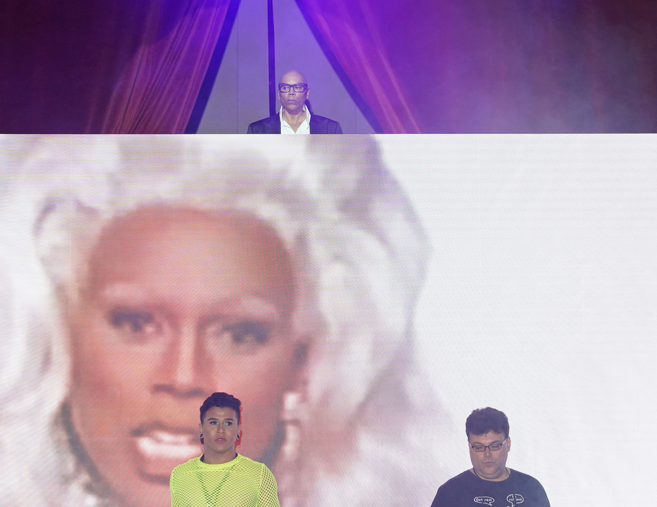 RuPaul, host of the show RuPaul's Drag Race, which birthed the RuPaul's DragCon UK event, DJs atop a screen displaying an image of RuPaul