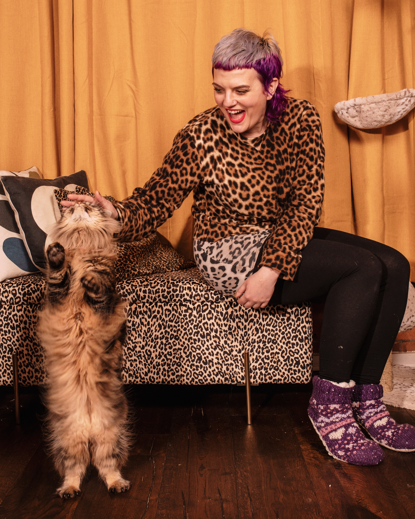 Kelly Bishop petting the head of her long-haired tabby cat who is standing on their hindlegs