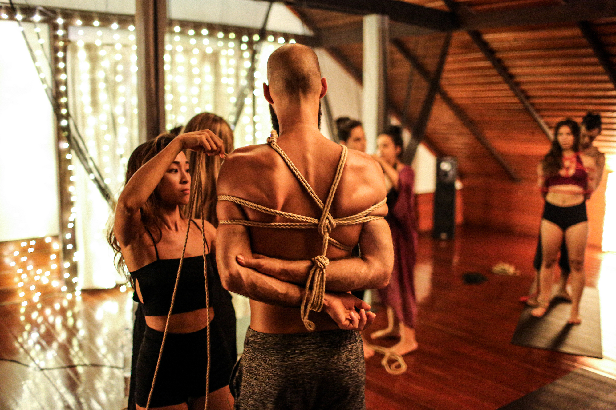 A woman ties up a man during a shibari rope workshop