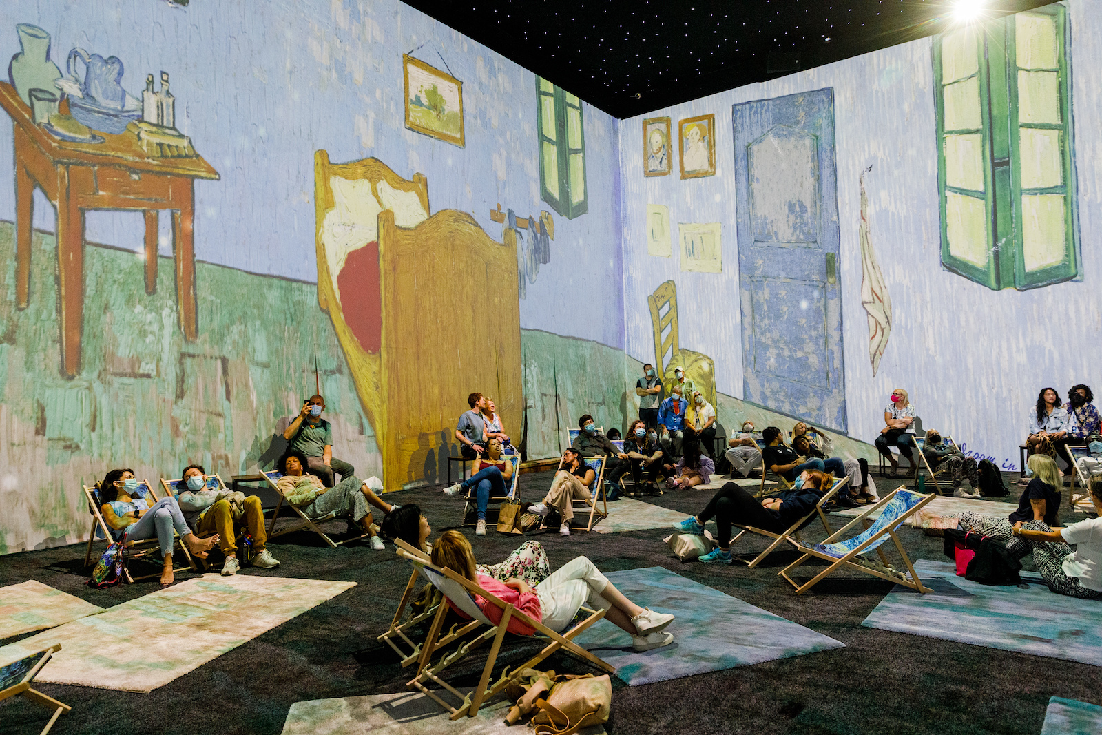 People reclining on deck chairs at the Van Gogh immersive exhibition.