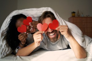 photo of a couple in bed on valentines day with construction paper hearts