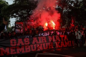 Demonstran membawa spanduk bertuliskan "Gas Air Mata Membunuh Kami"