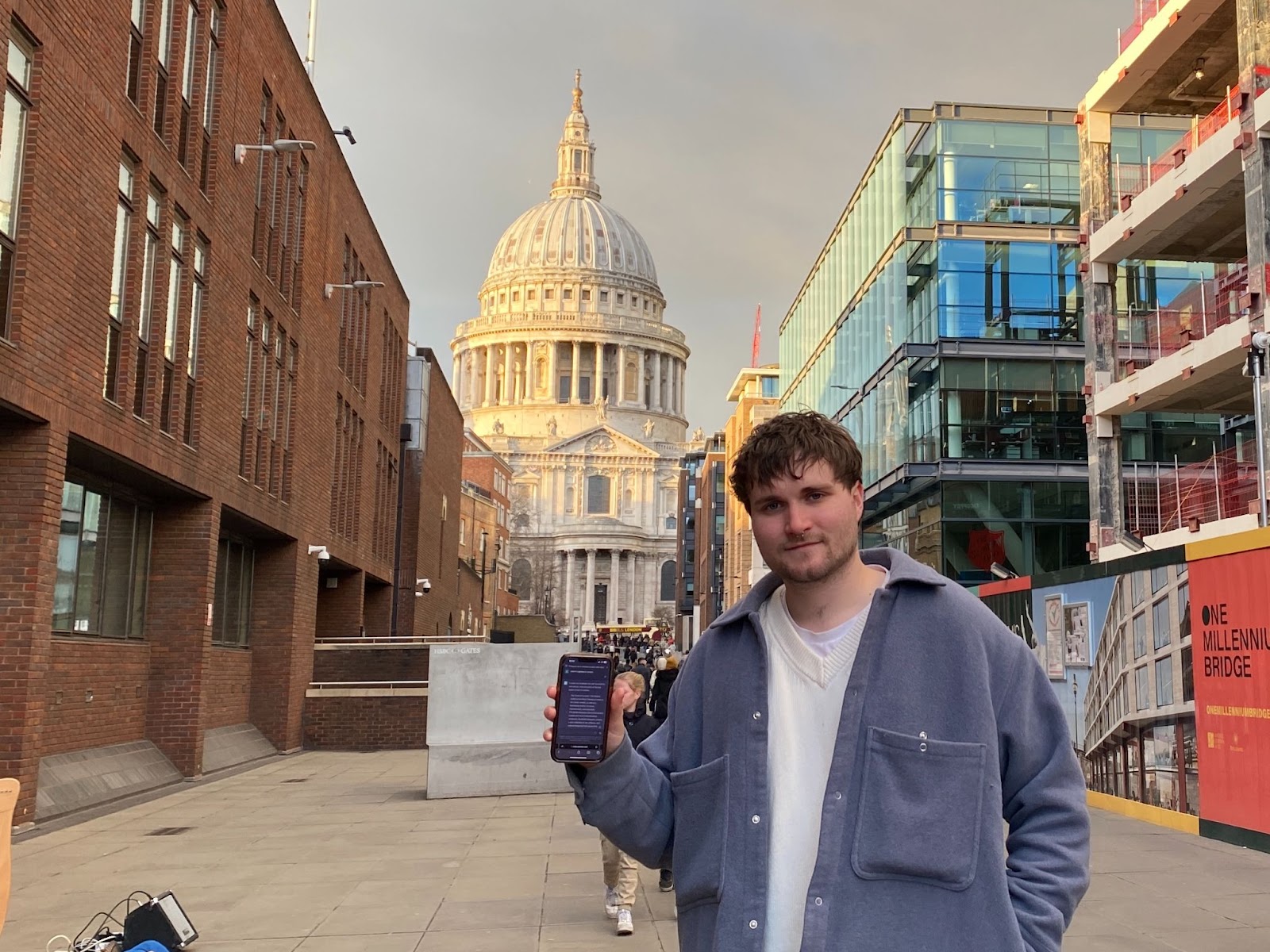 A man standing outside St Pauls Cathedral holding up phone