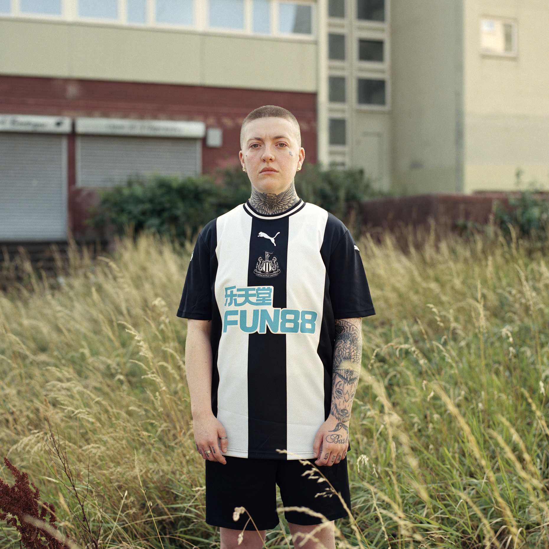Sal, Gateshead, Newcastle: A tattooed butch lesbian in football jersey in a field