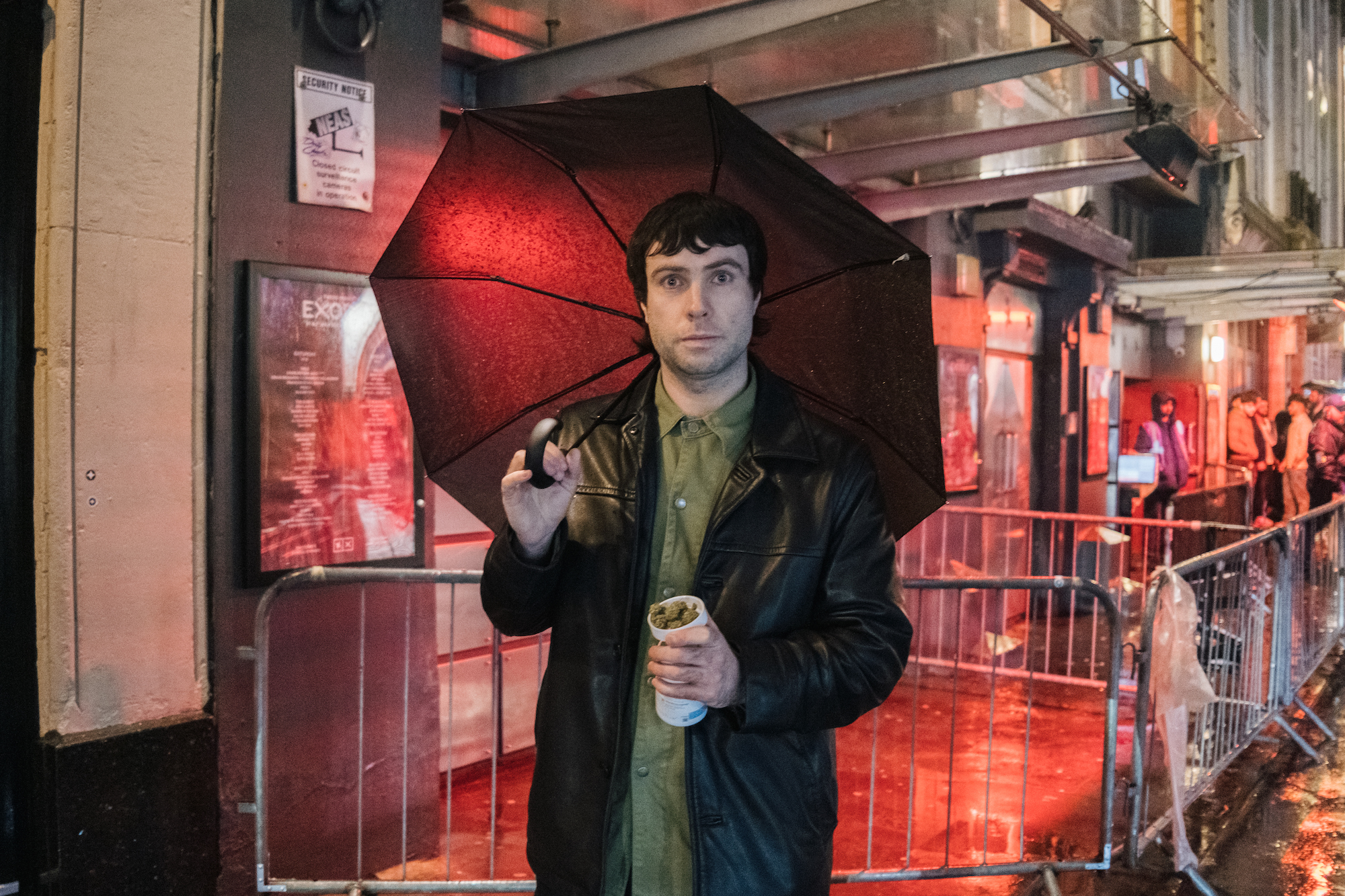 A man in leather jacket holds up prescription bottle of medical cannabis outside fabric nightclub in London