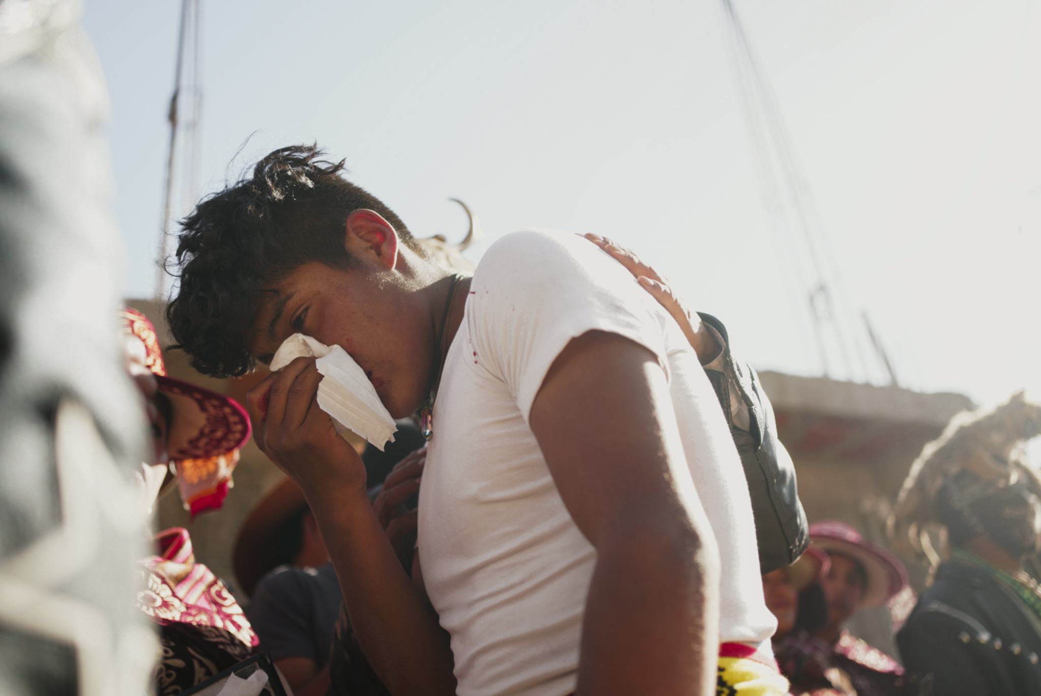 Takanakuy, Peru – young man surrounded by crowd blotting his nose with a tissue.