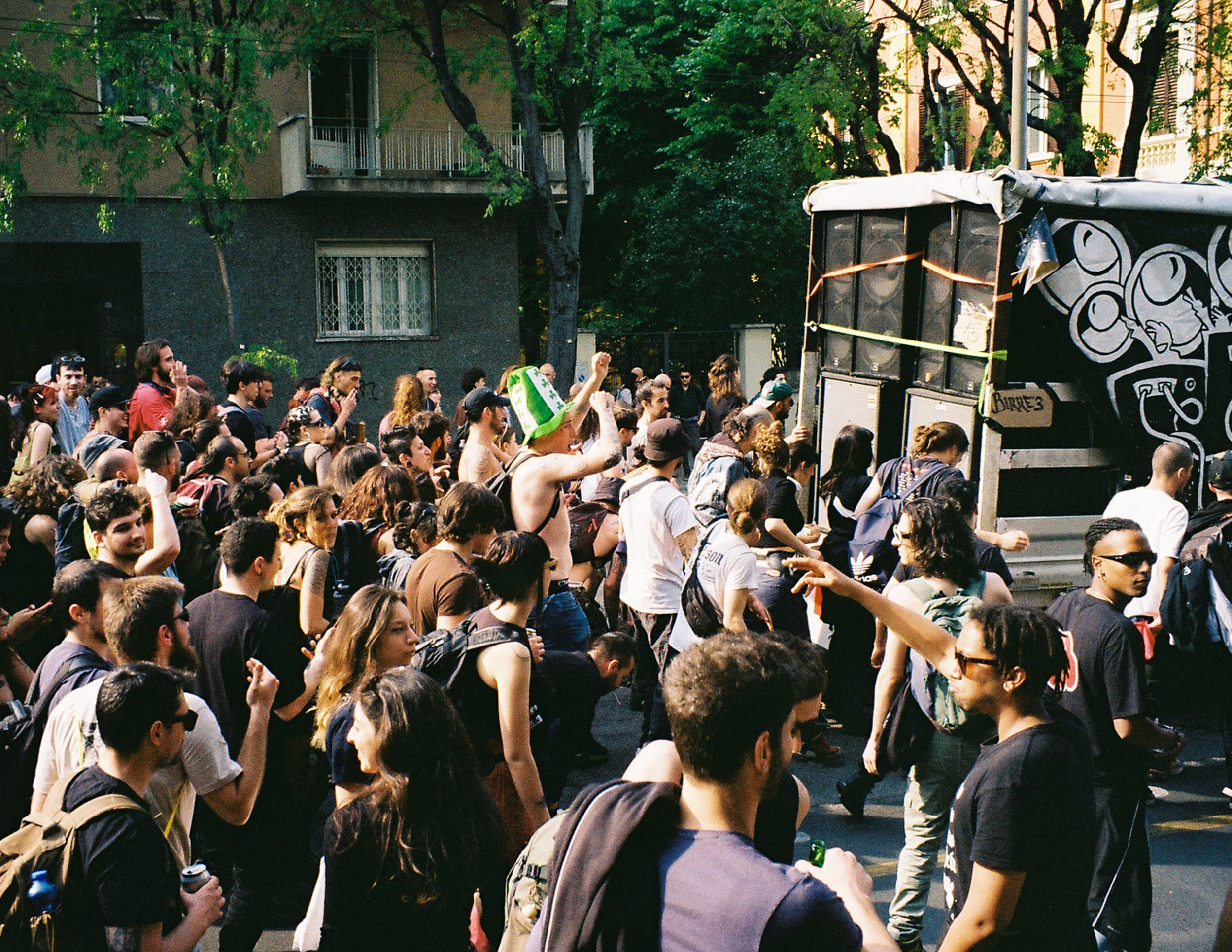 Eine menge läuft tanzend hinter einem Lastwagen, auf dem ein Soundsystem installiert ist