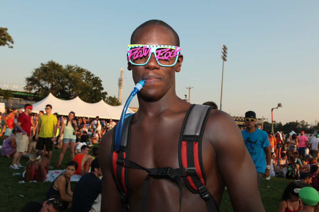Een shirtloze man met een jaren 80 zonnebril op Randall's Island, New York.