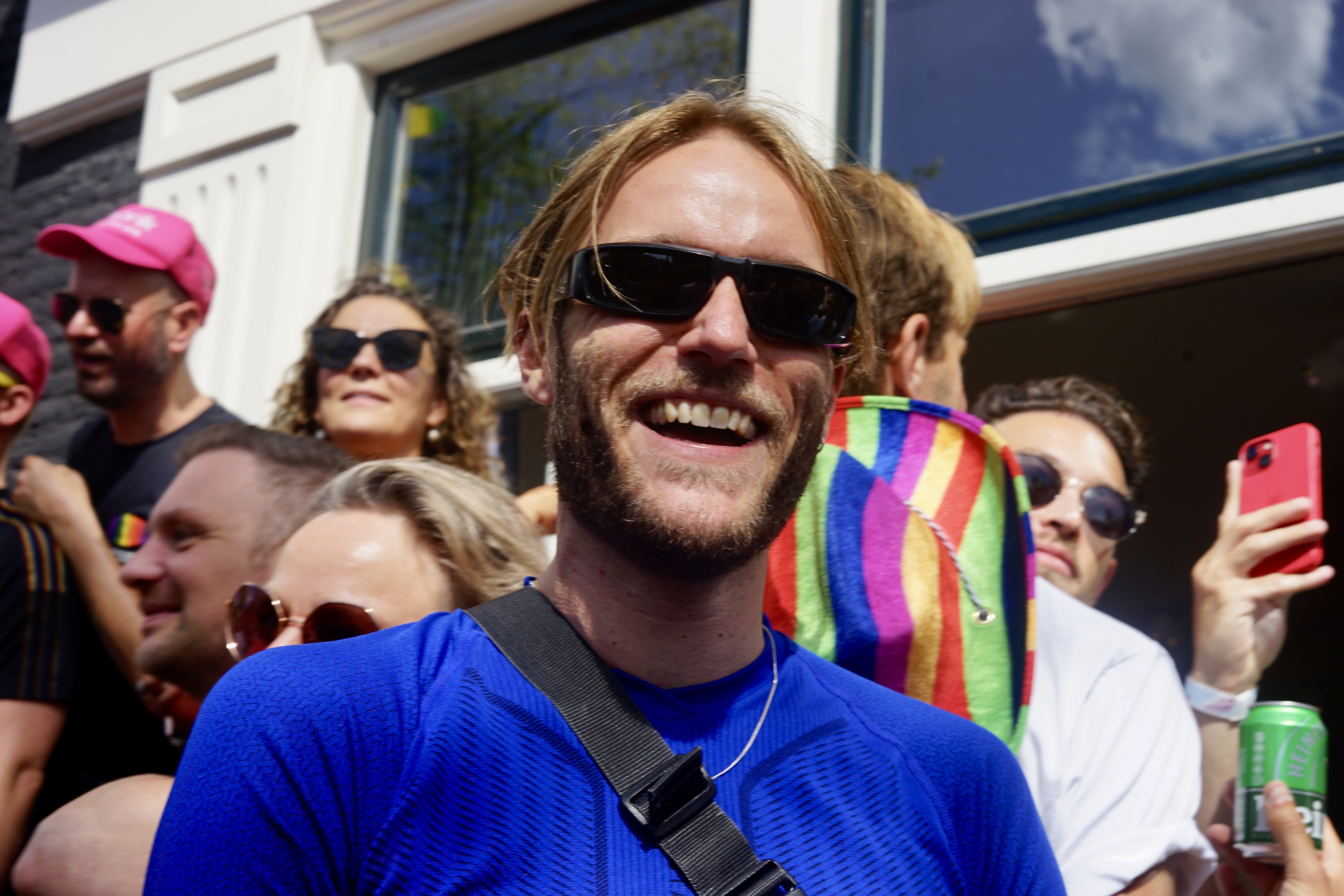 Ein weißer blonder Mann mit Sonnenbrille lächelt in die Kamera