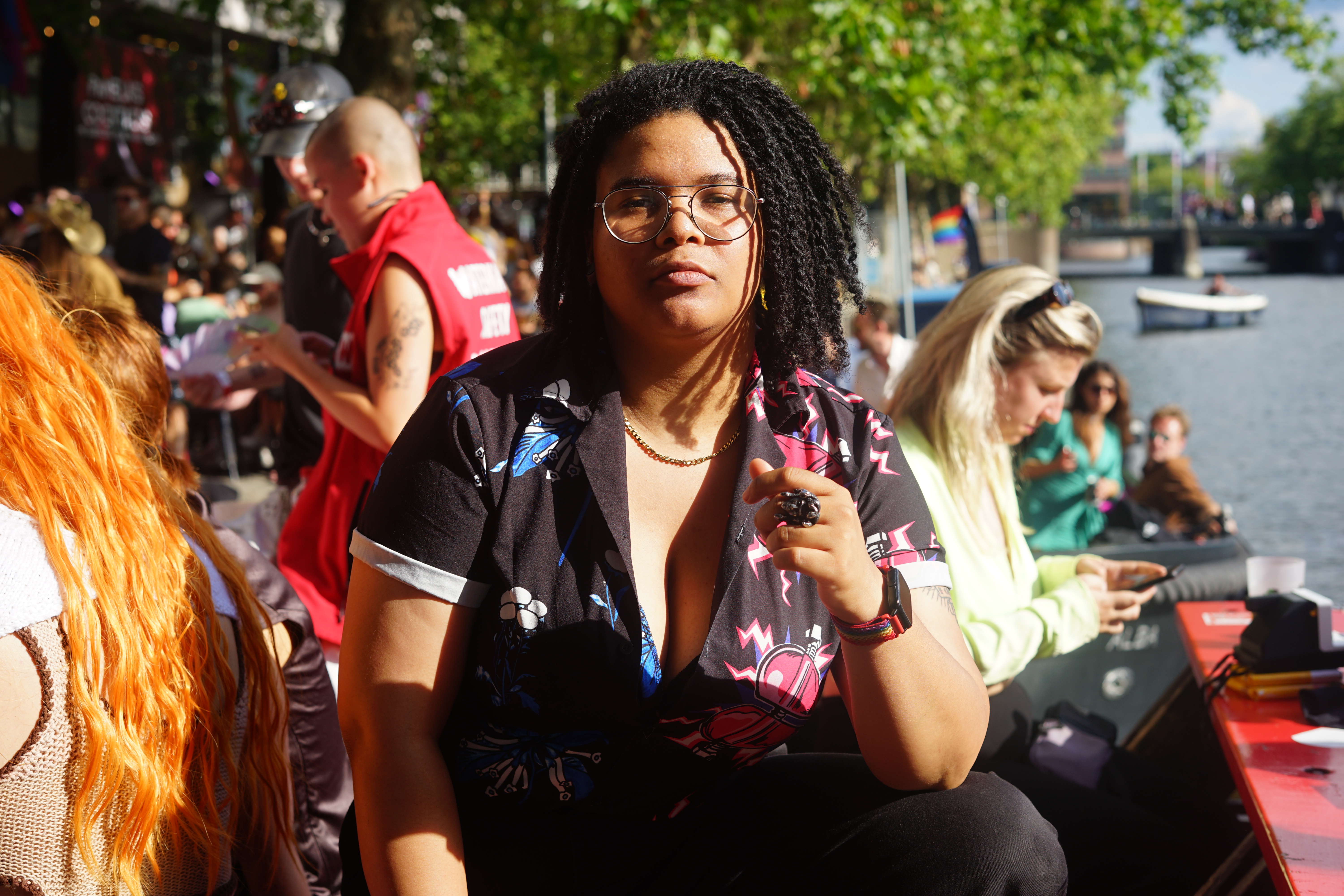 Eine schwarze Frau mit Dreadlocks und Brille schaut in die Kamera