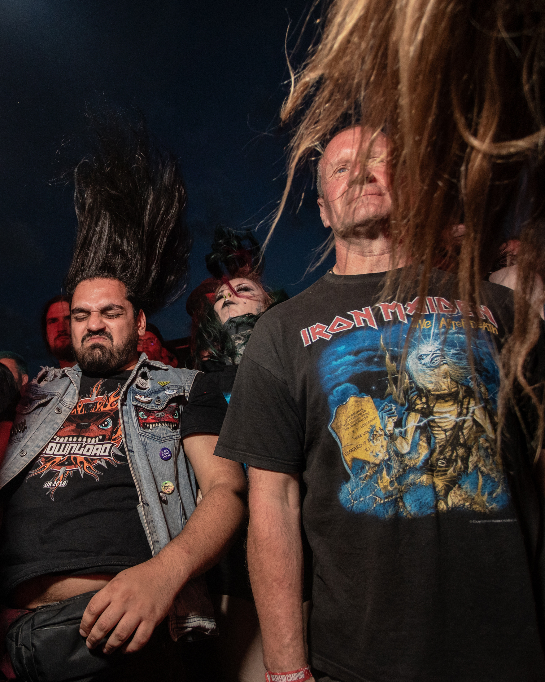 Menschen in Metalshirts beim Headbangen