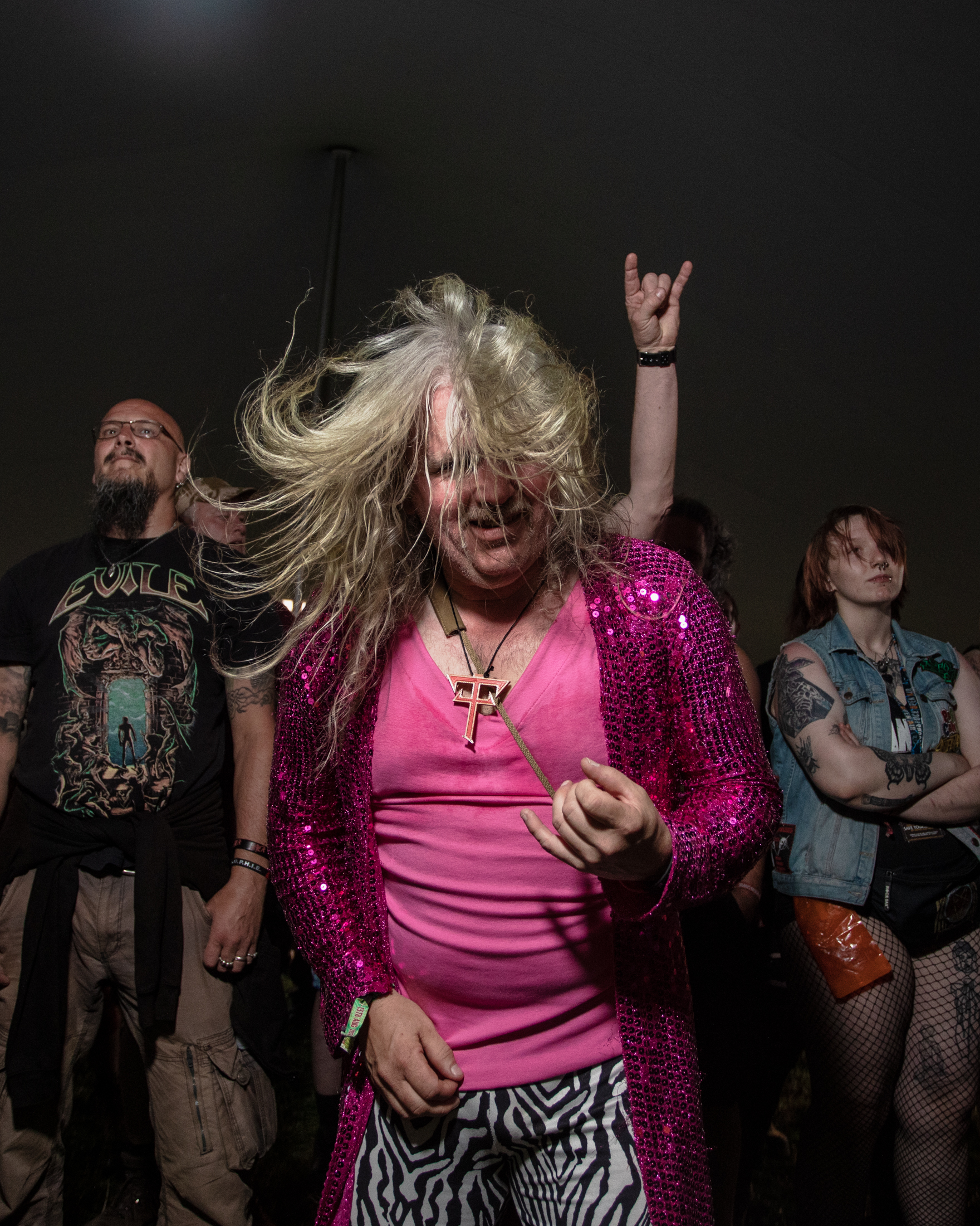 Ein Mann in pinken und mit Pailetten besetztem Outfit spielt Luftgitarre