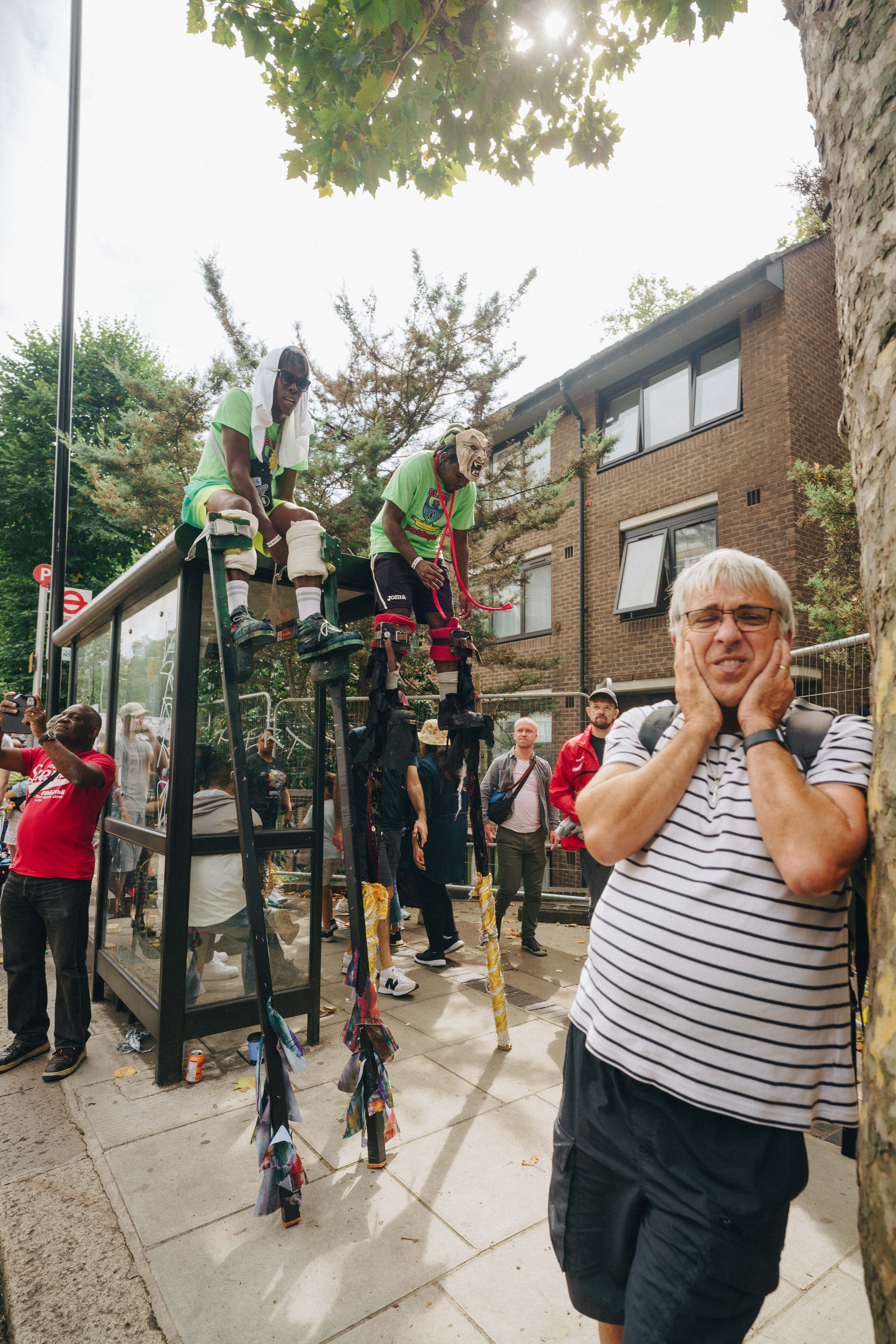 Notting Hill Carnival 2023, London: A man stuffs his ears in front of a bus stop