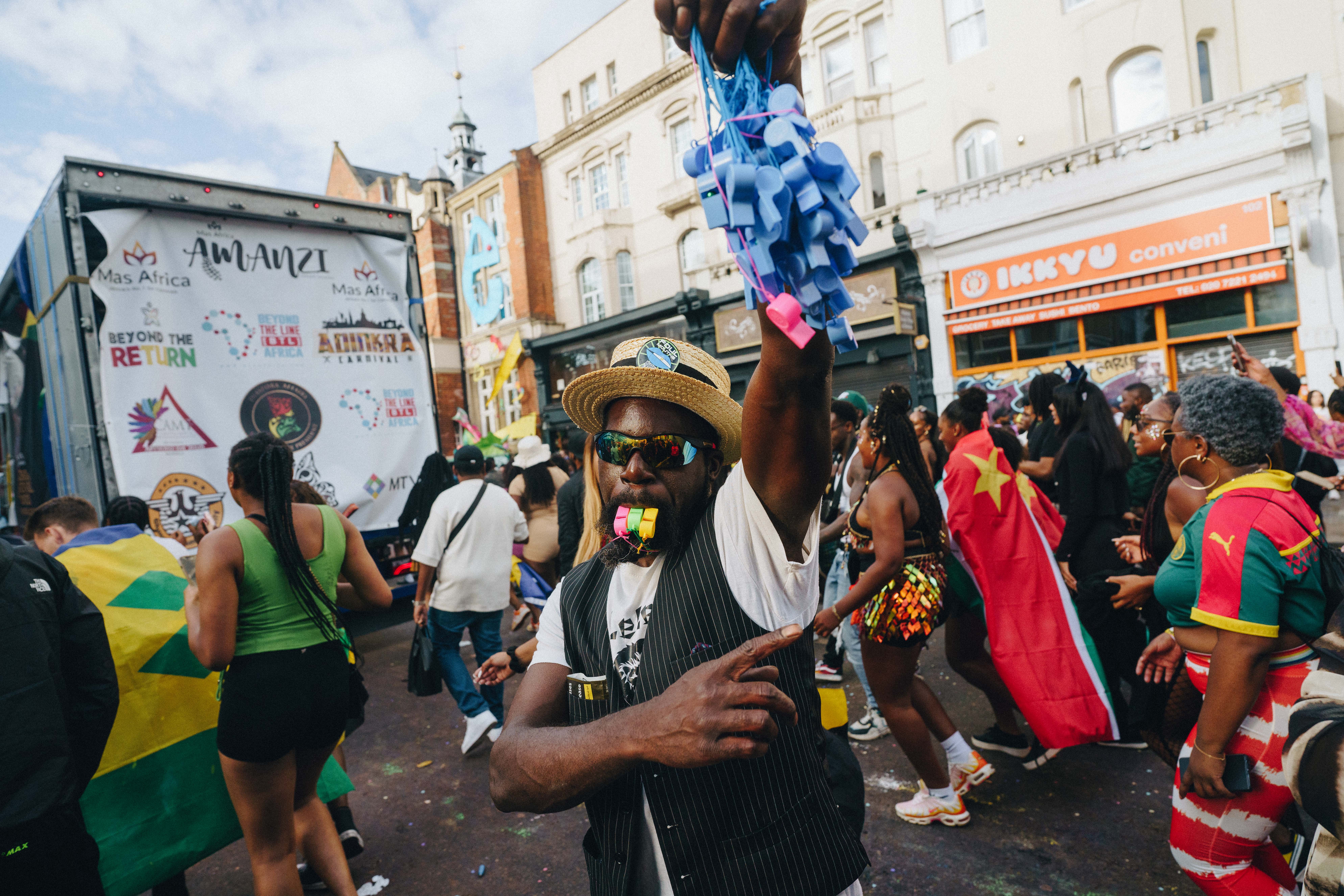 Notting Hill Carnival 2023, London: A man holds up an armful of whistles