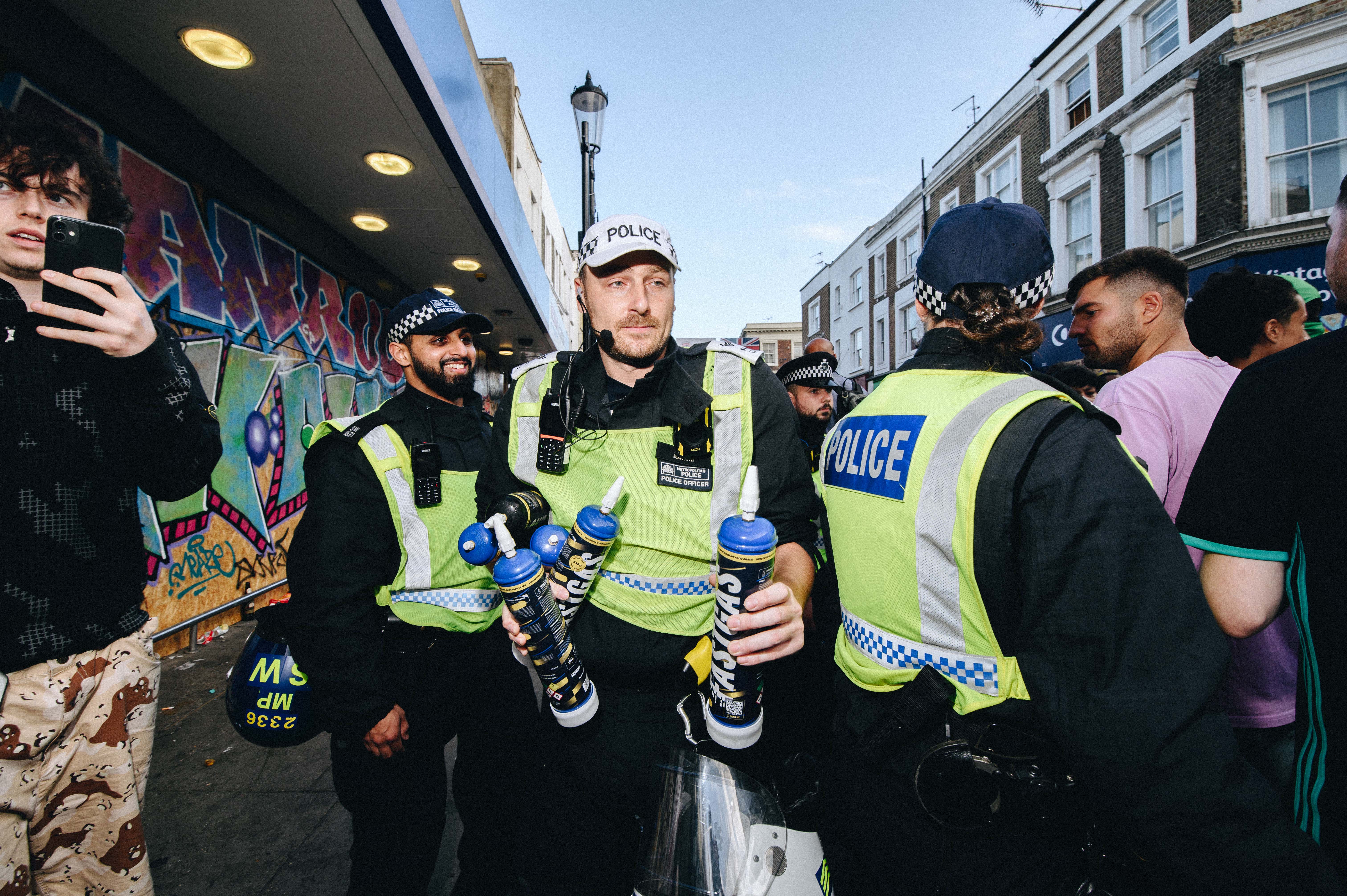 Notting Hill Carnival 2023, London: Three police officers holding confiscated laughing gas canisters