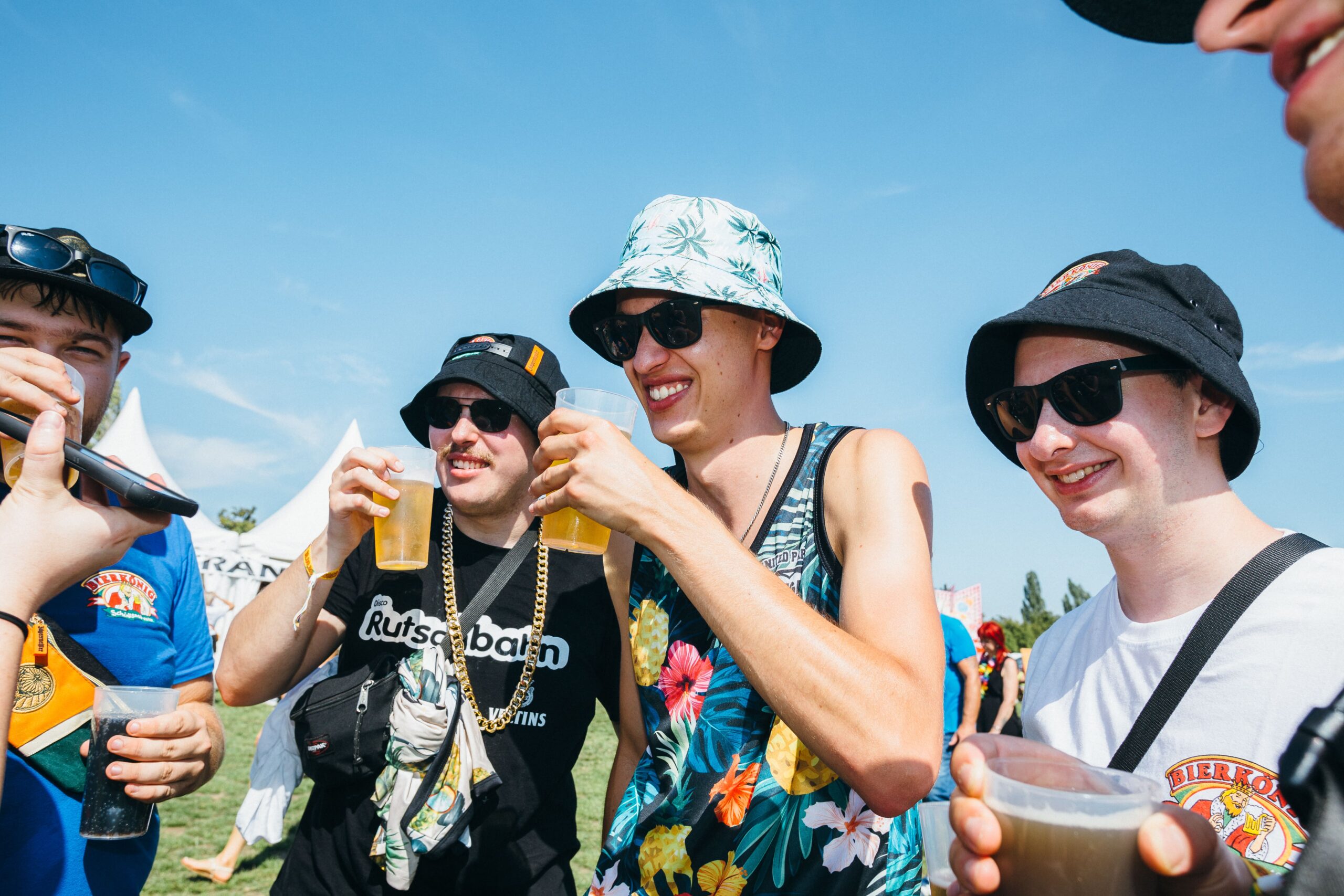 Eine Freundesgruppe aus fünf Männern, alle trinken ein Bier
