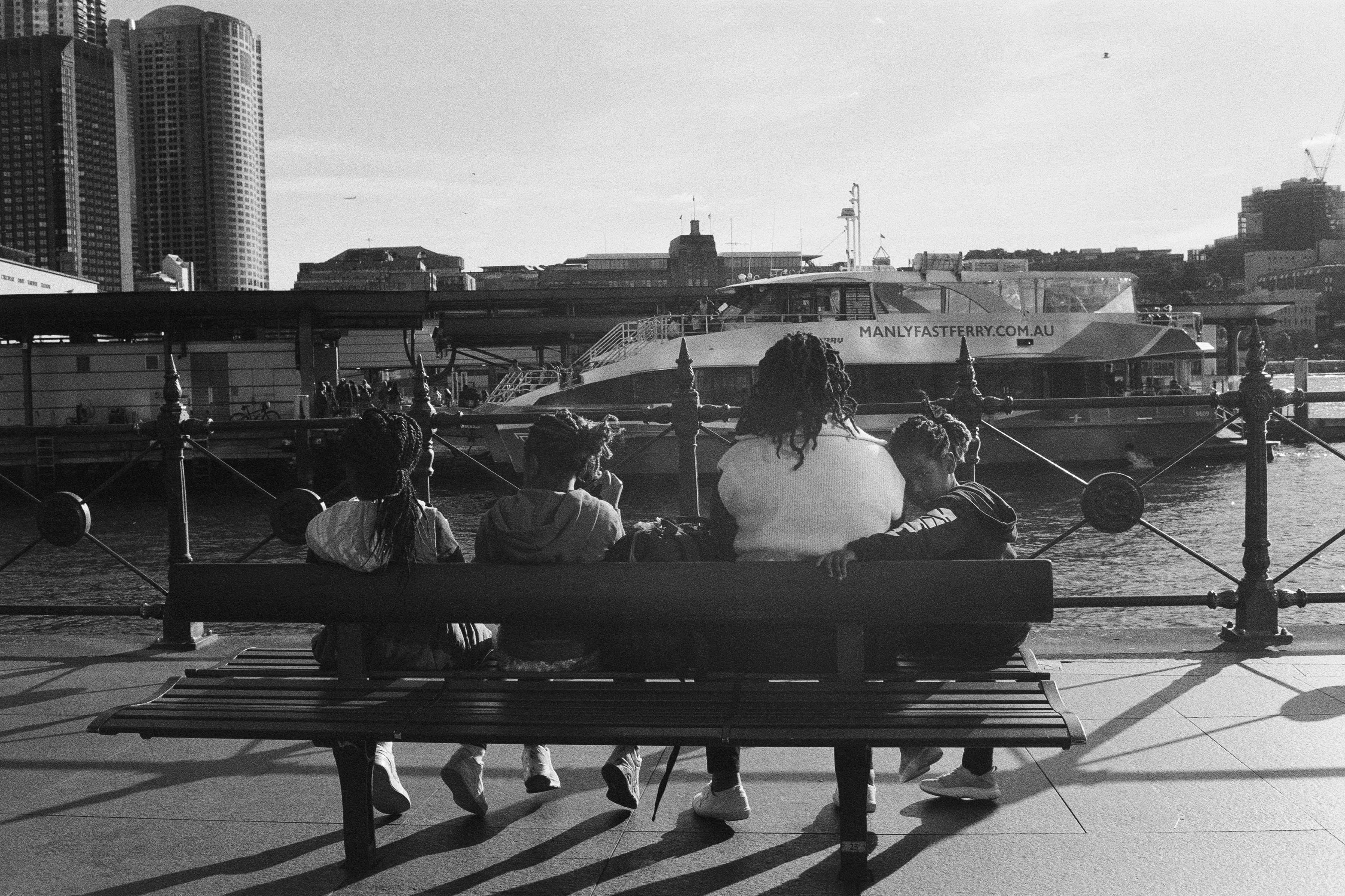 Family sits on bench facing the harbour