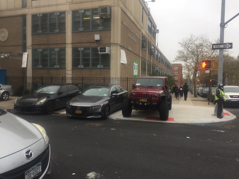 Red Jeep parked on sidewalk