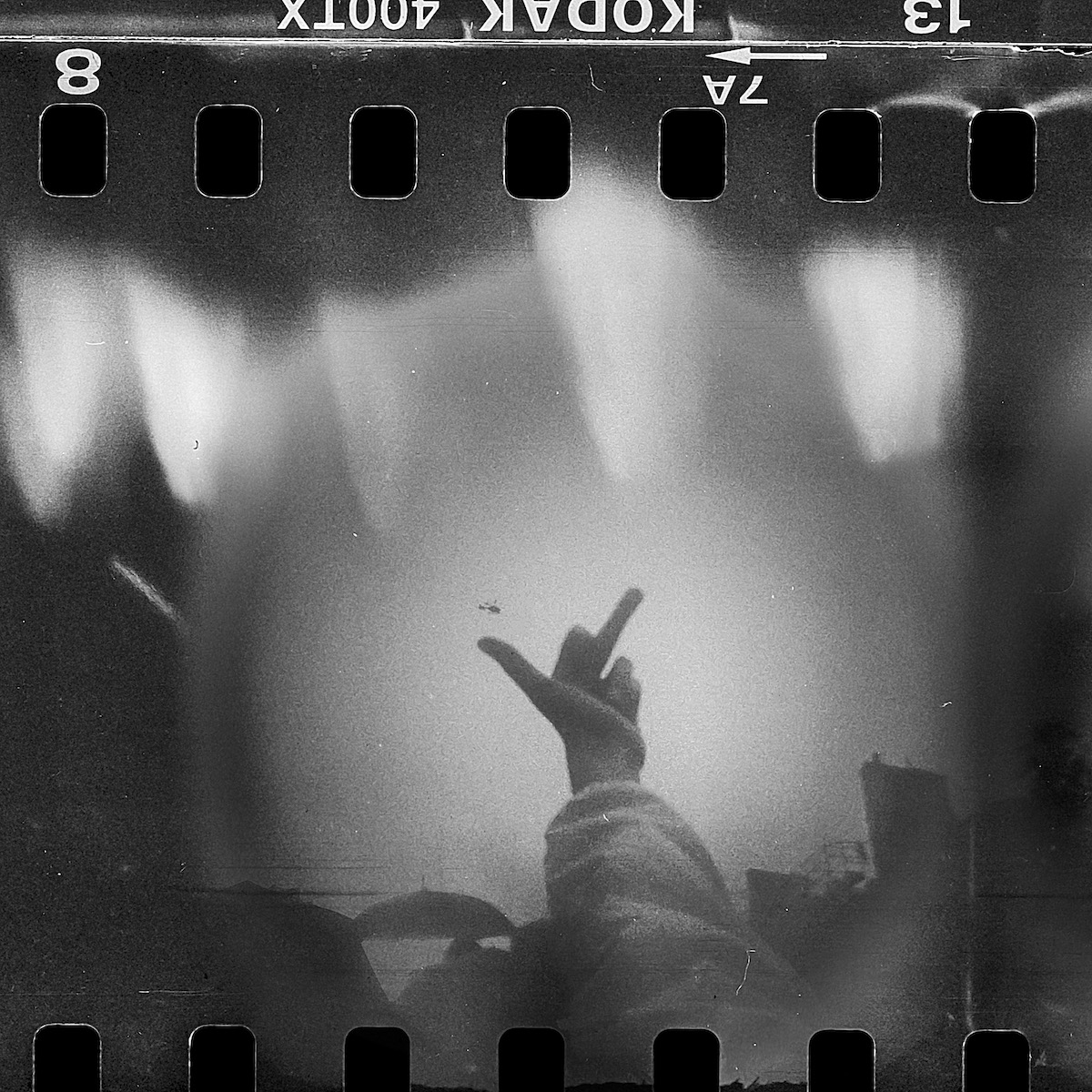 Steven Monteau photos with police weapons: black and white negative of a hand giving the middle finger in the air
