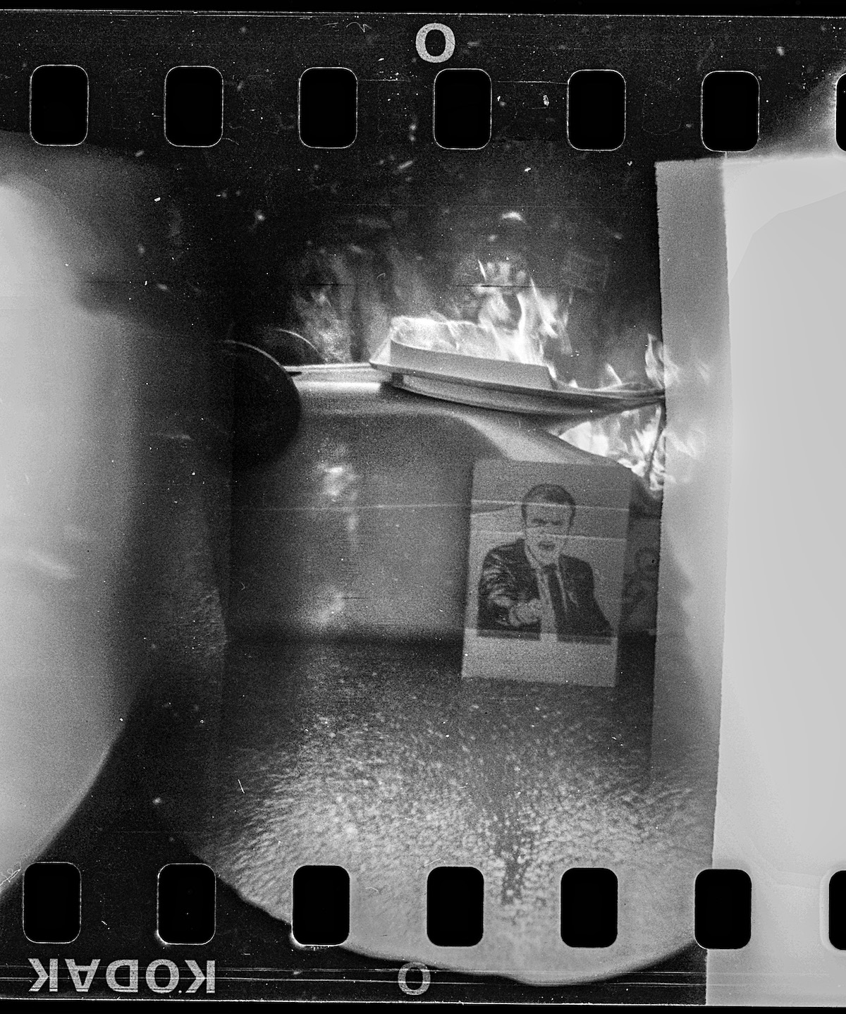 Steven Monteau photos with police weapons: black and white negative of a photo of Macron and fire
