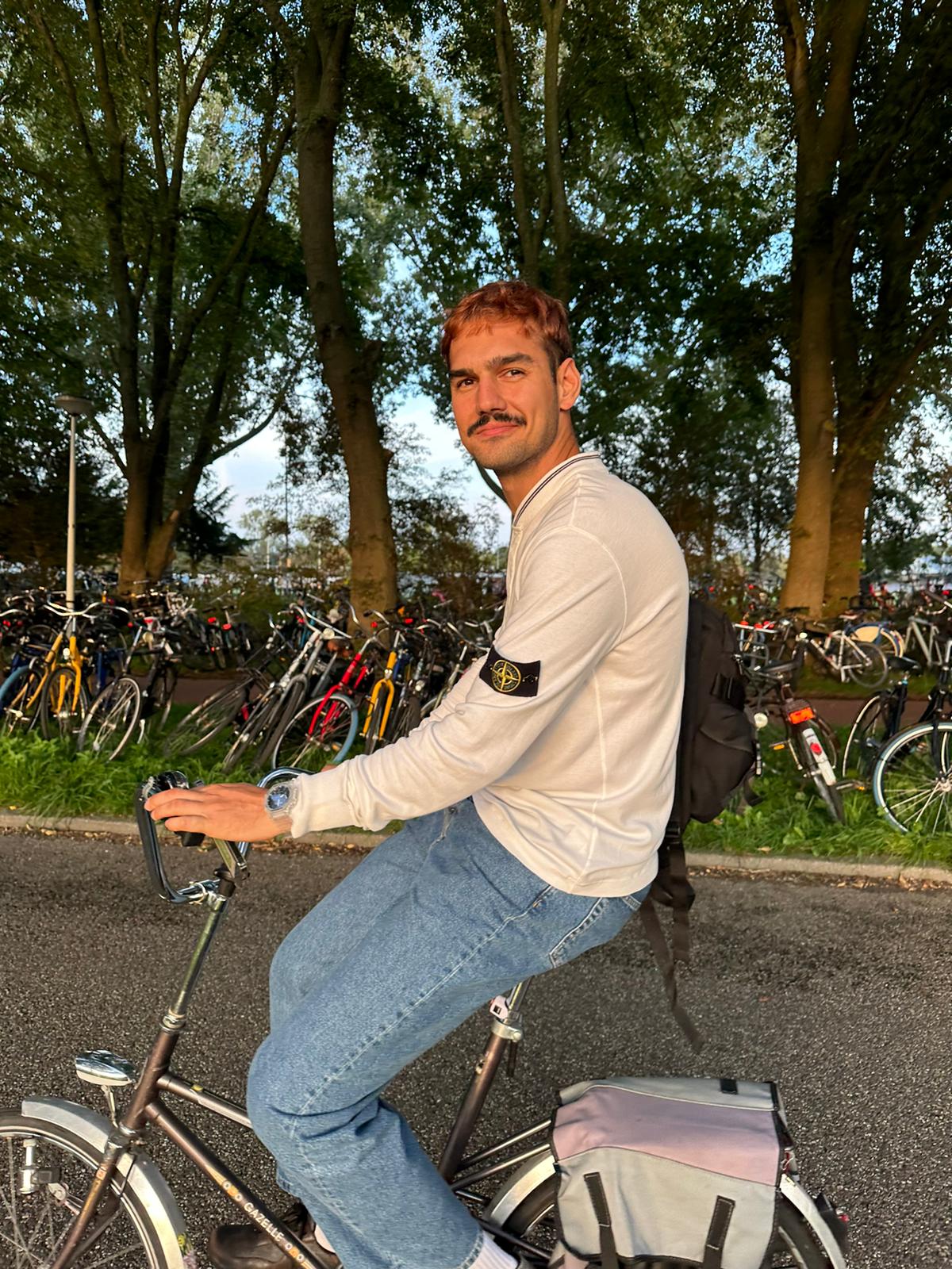 Ein junger Mann mit schwarzem Schnurrbart sitzt bei sonnigem Wetter auf einem Rad