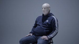 A man wearing a mask and sitting in a chair