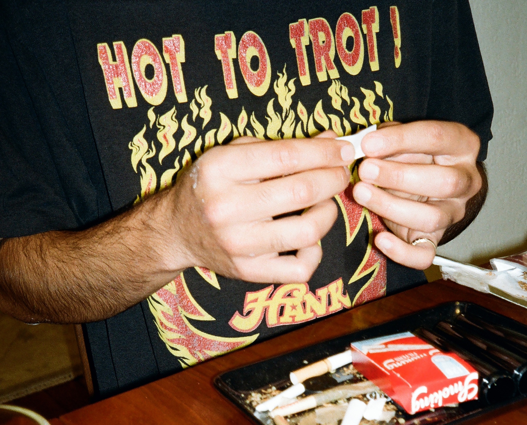 a man rolls papers at a dining table