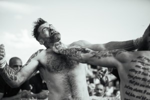A young white man recoils after being punched in the face by a rival combatant during a bare knuckle fighting bout