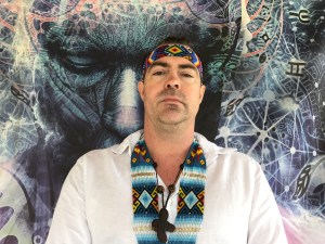 A man poses for a photo in front of wall art.