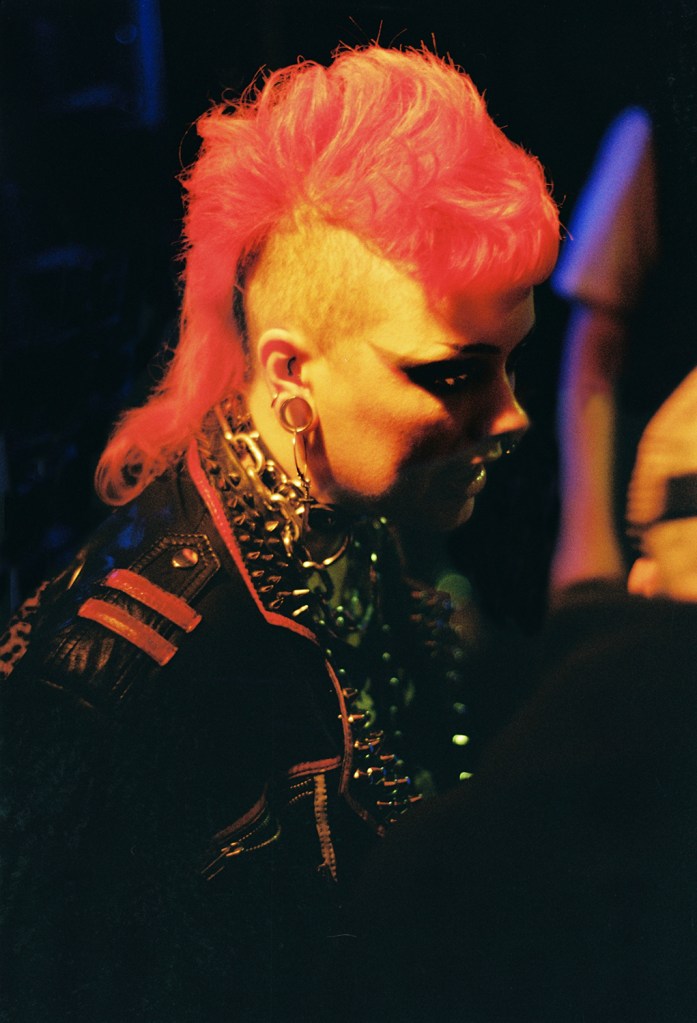 A woman with pink red hair styled in a mohican at a hardcore punk show in Berlin