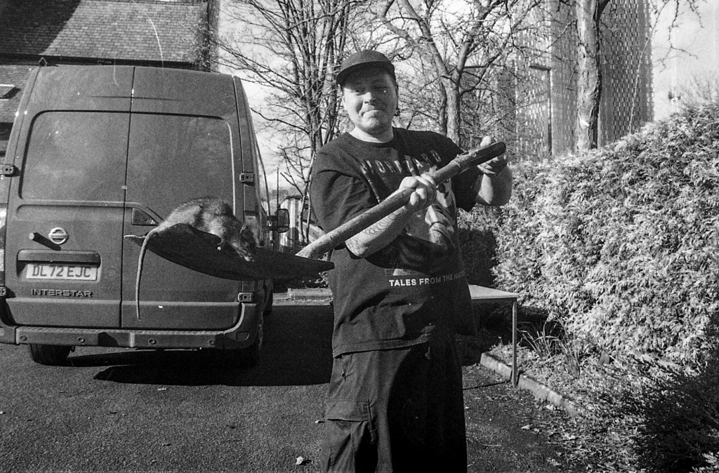 A man holds out a shovel with a dead rat on it