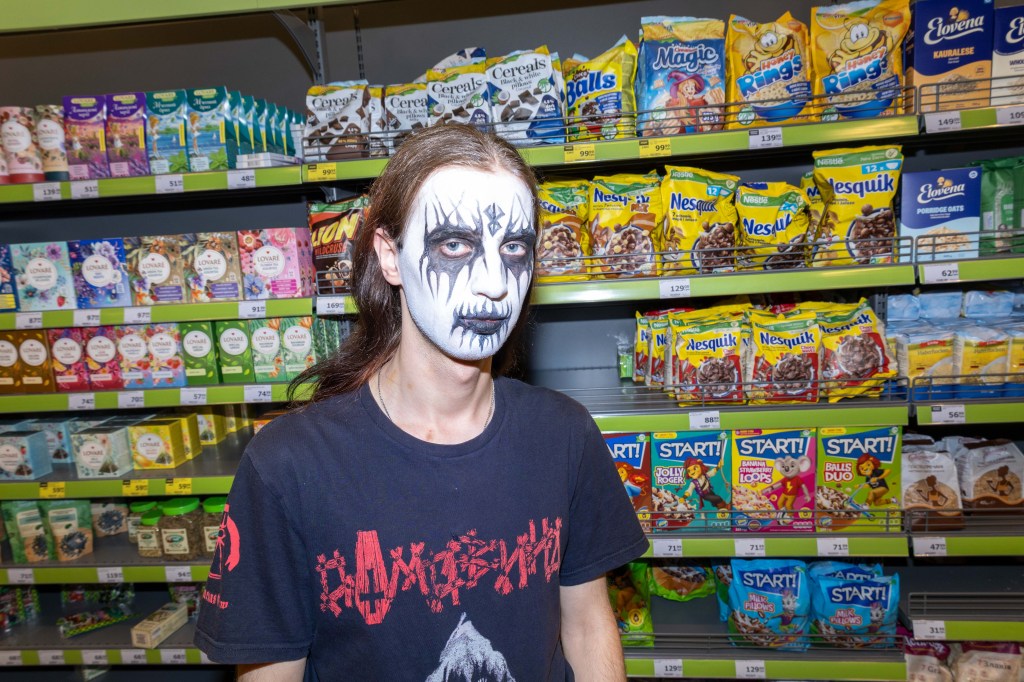 A goth poses for a photo in a supermarket