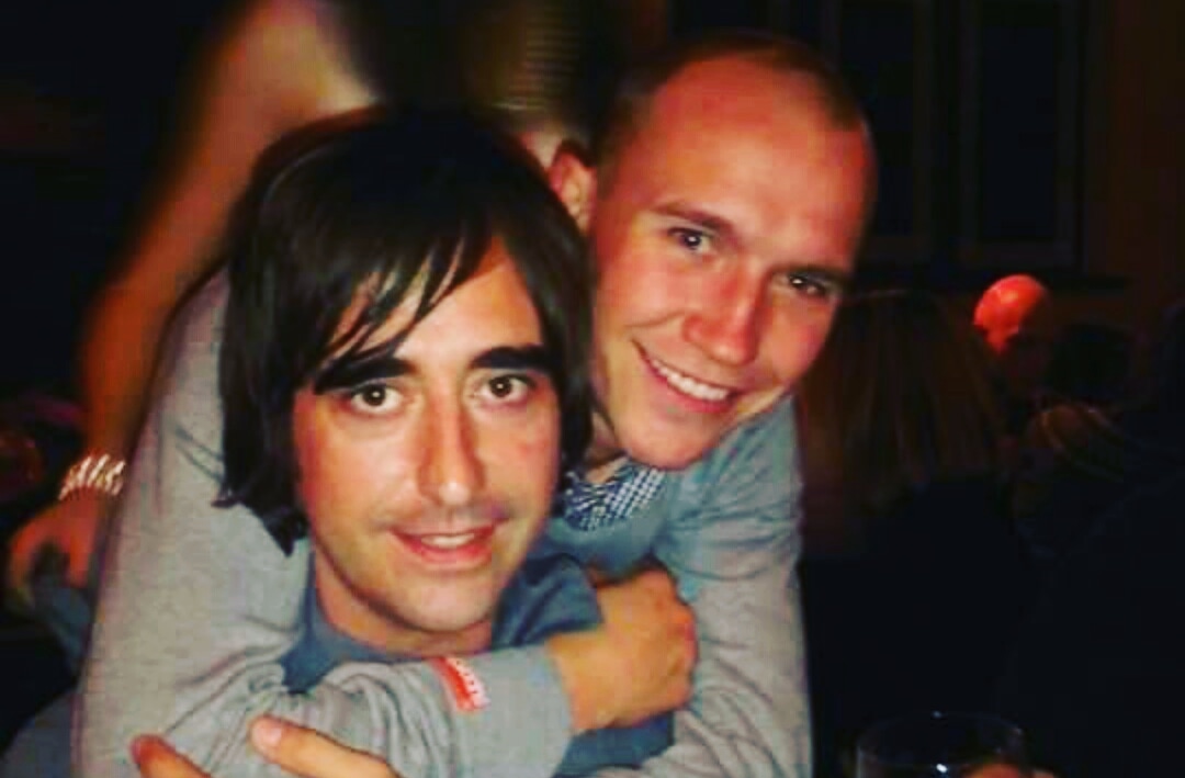 Two brothers pose in a bar, smiling
