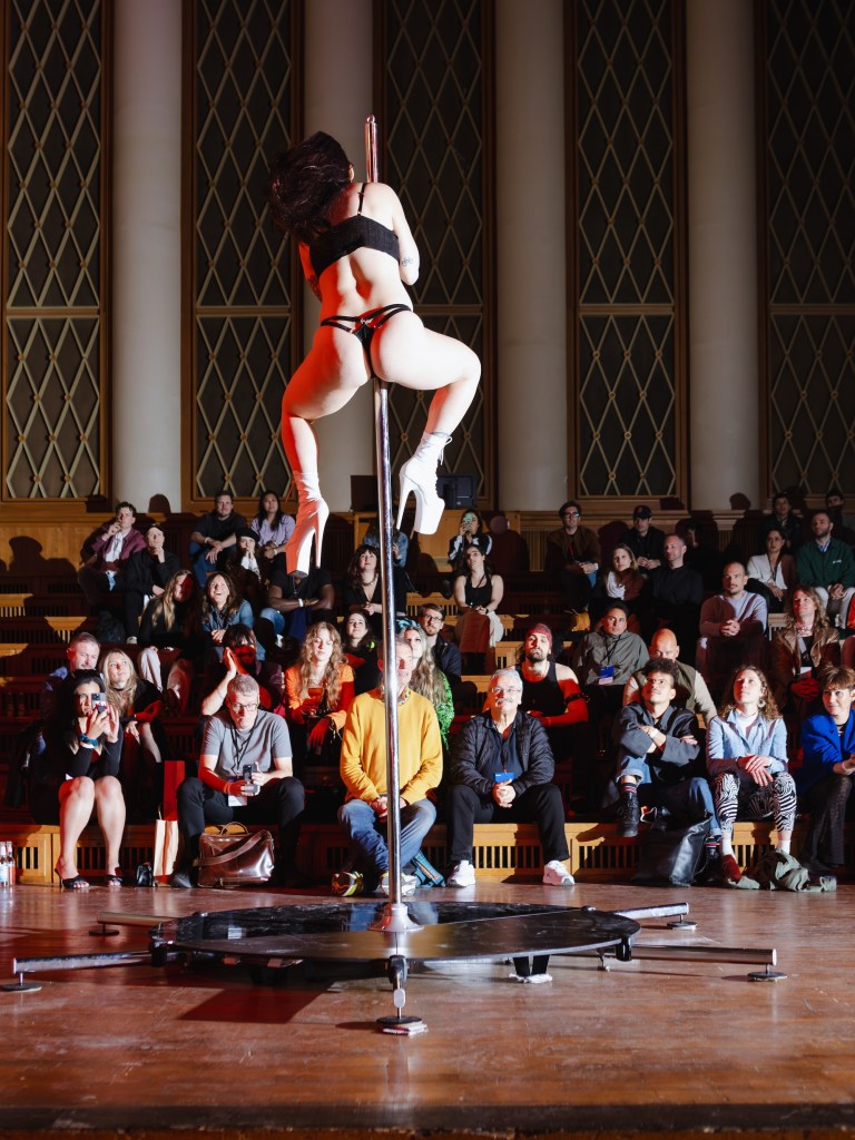 One stripper performs on a pole for a crowd